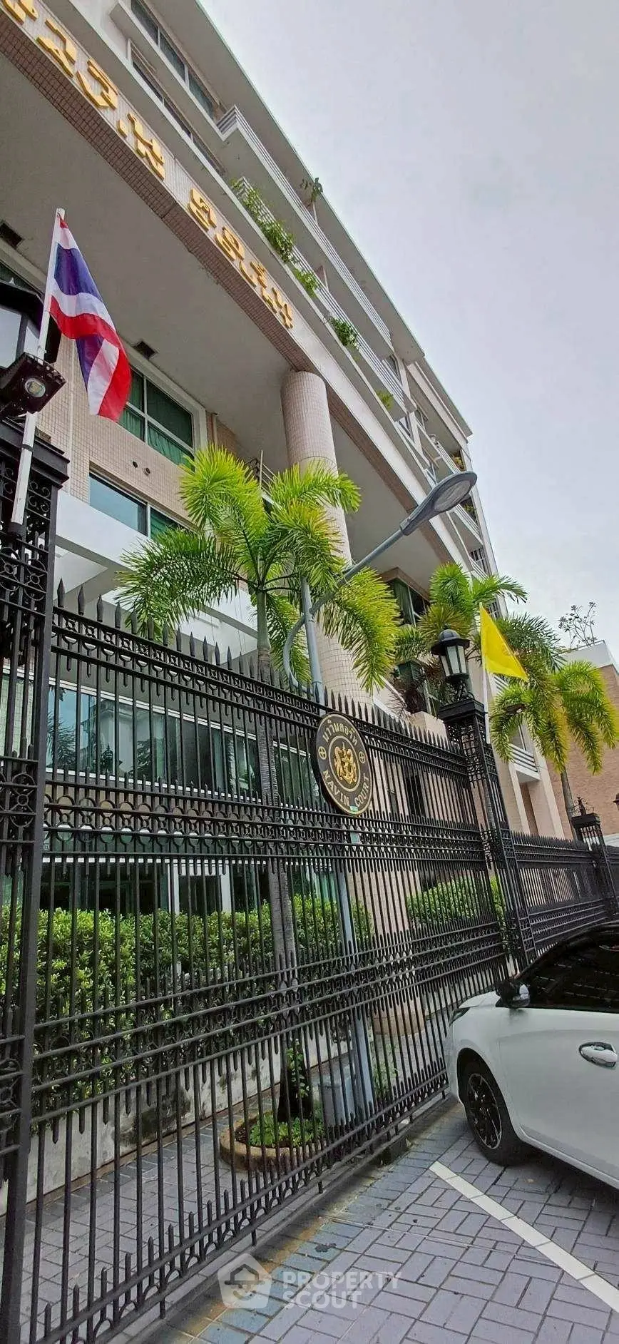 Modern building exterior with gated entrance and lush greenery