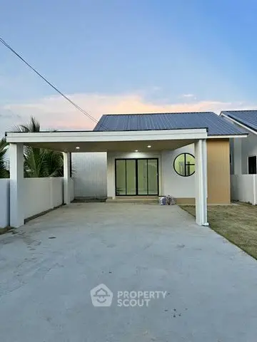 Modern single-story house with spacious driveway and contemporary design.