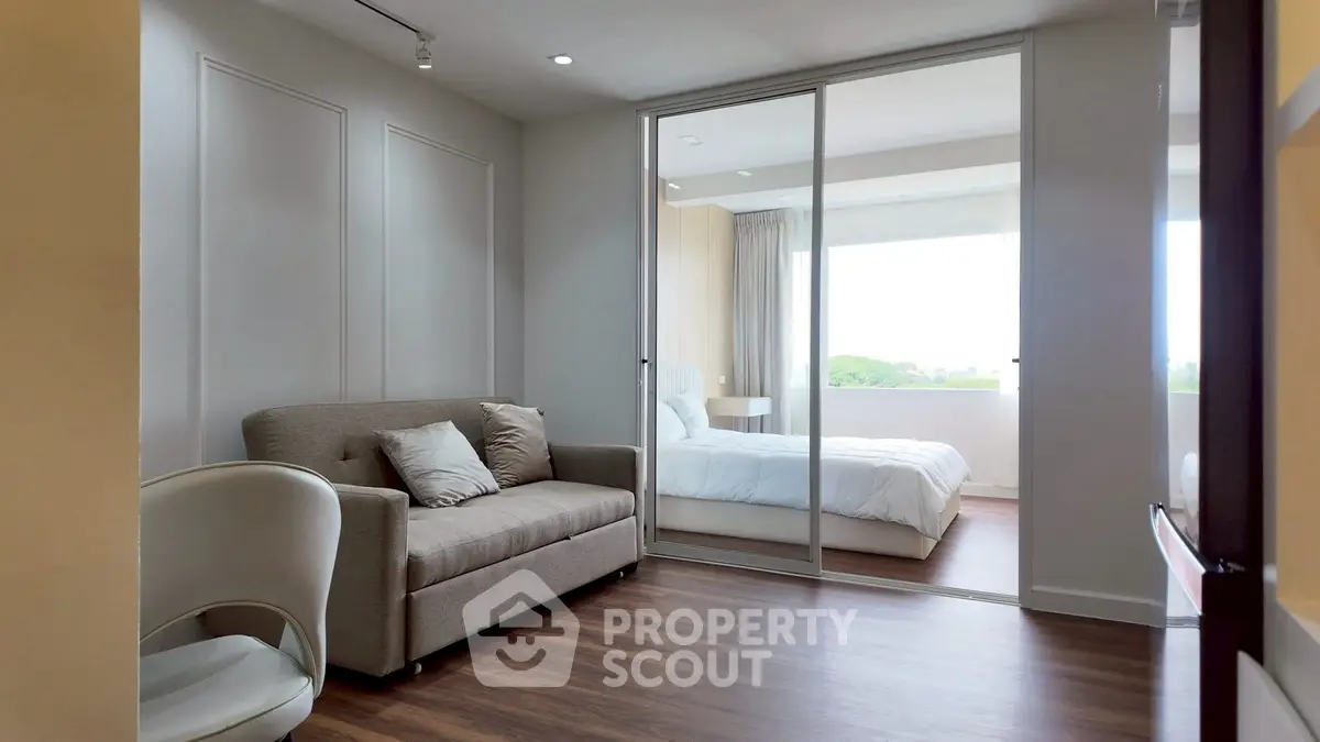 Modern bedroom with sliding glass doors and cozy seating area, featuring natural light and elegant decor.