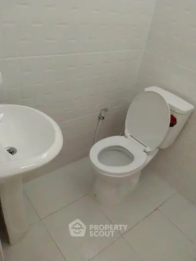 Compact bathroom with white fixtures and tiled walls