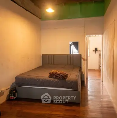 Cozy bedroom with wooden flooring and modern bed frame, perfect for relaxation.