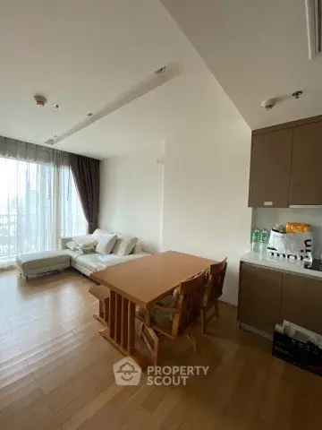 Spacious living room with wooden flooring and large windows offering natural light.