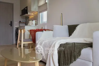 Modern living room with cozy sofa and compact kitchen in open layout apartment.