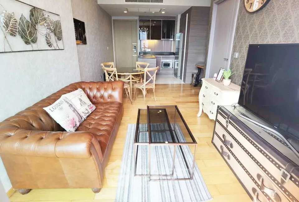 Stylish living room with leather sofa and modern kitchen in open layout apartment.
