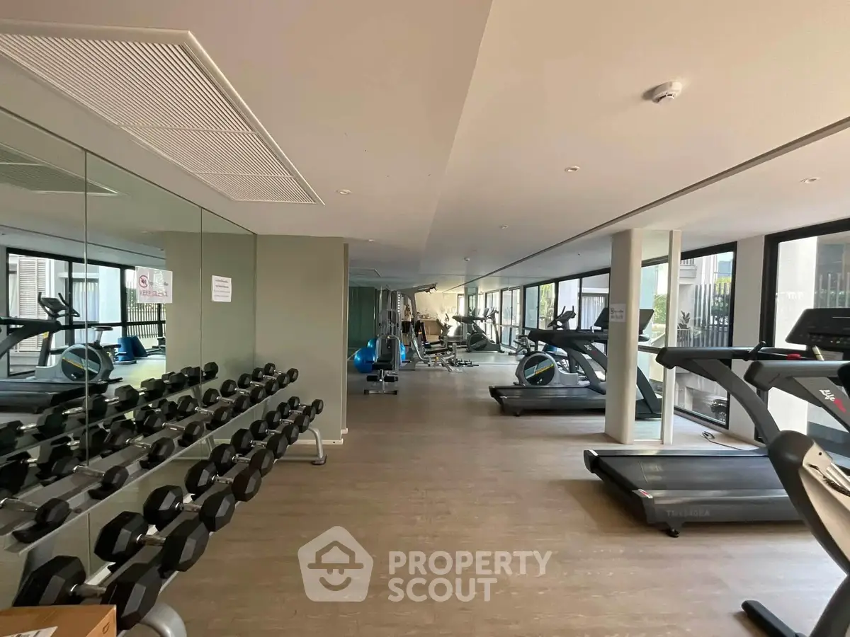 Spacious modern gym with state-of-the-art equipment and large windows for natural light.