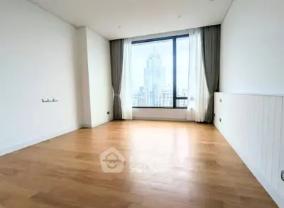 Spacious empty room with large window offering stunning cityscape view, perfect for customization.