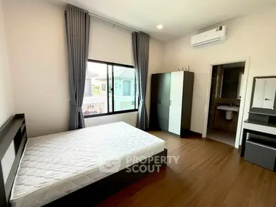 Spacious bedroom with modern furnishings and large window offering natural light.