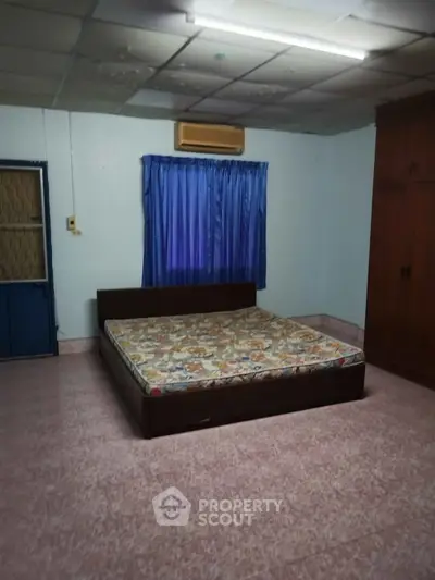 Spacious bedroom with large bed and wardrobe, featuring tiled flooring and air conditioning.