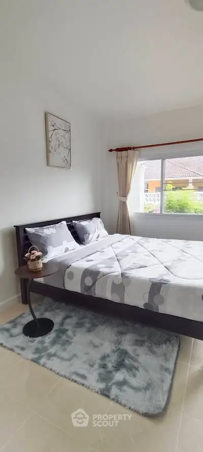 Cozy bedroom with modern decor and large window offering natural light.