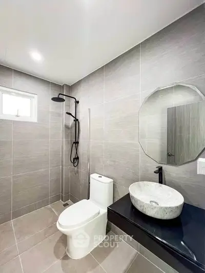 Modern bathroom with sleek fixtures and minimalist design, featuring a stylish vessel sink and walk-in shower.