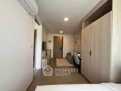 Modern studio apartment with sleek wooden flooring and stylish furniture, featuring a cozy living area and dining space.