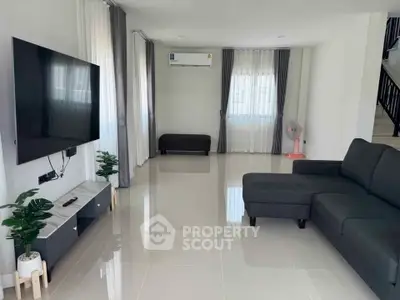Spacious modern living room with sleek furniture and large TV, perfect for relaxation.