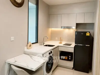 Modern kitchen with sleek appliances and marble countertop in a compact layout.