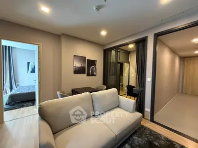 Modern living room with cozy sofa and stylish decor adjacent to a bedroom and dining area.