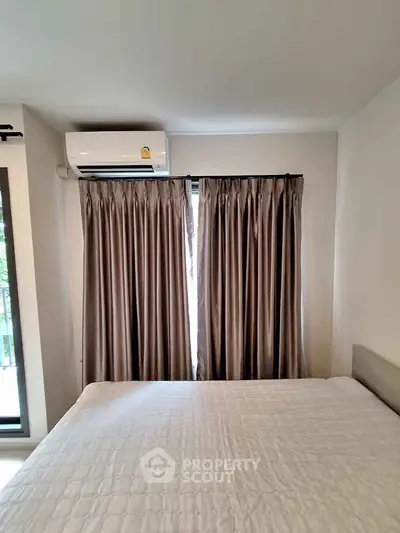 Cozy bedroom with air conditioning and elegant curtains, perfect for a comfortable living experience.