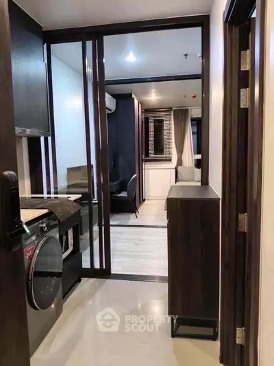 Modern apartment hallway leading to a stylish living area with sleek furnishings and contemporary design.