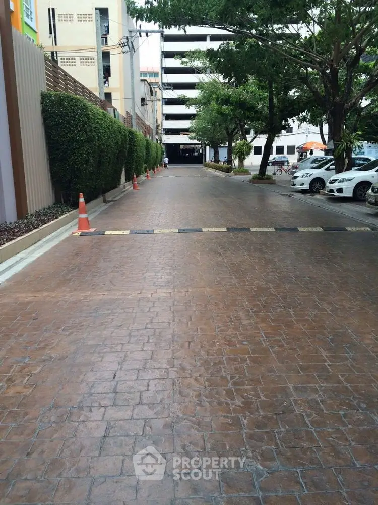 Spacious parking area with trees and modern building backdrop