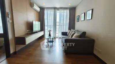 Modern living room with large window and city view, featuring sleek furniture and wooden flooring.