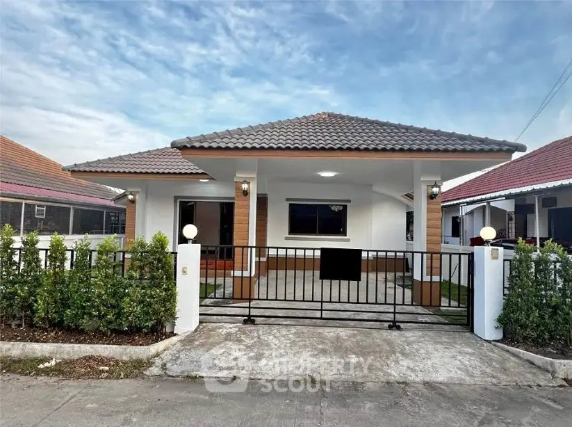 Charming single-story home with a gated entrance and lush greenery.