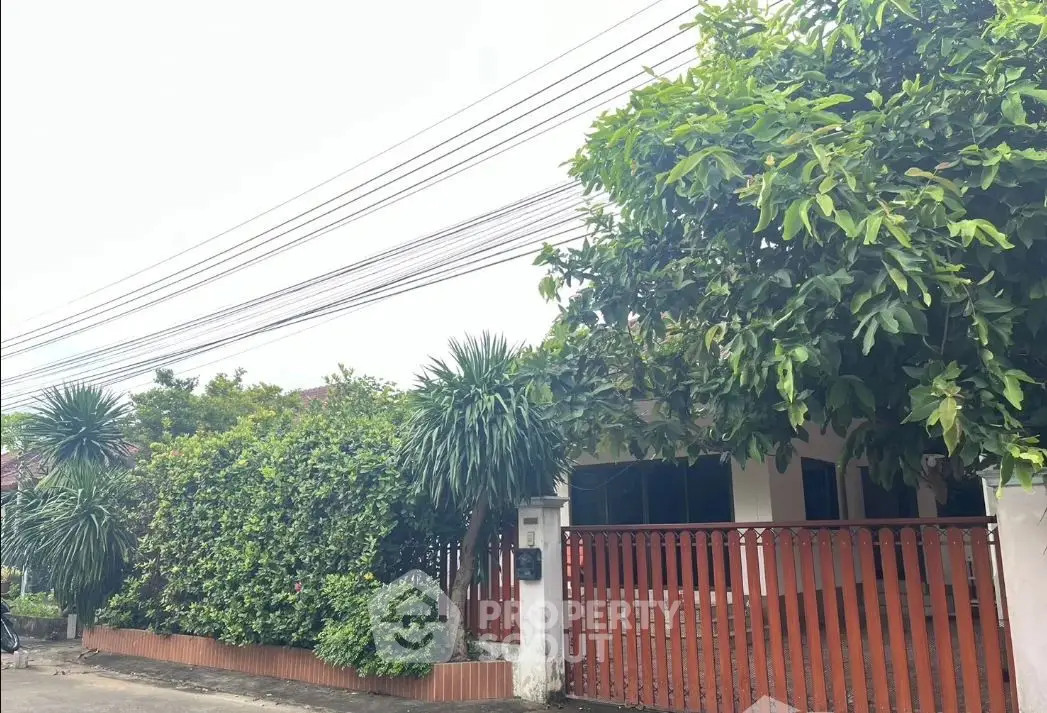 Charming suburban home with lush greenery and wooden fence, perfect for family living.