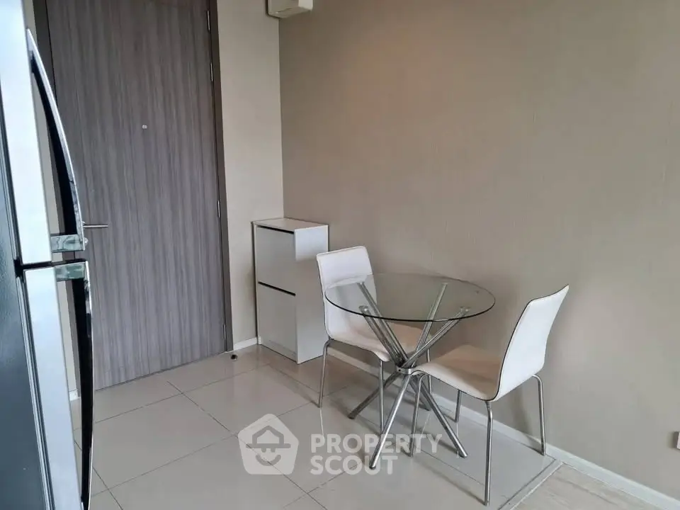Modern minimalist dining area with glass table and white chairs in a cozy apartment.