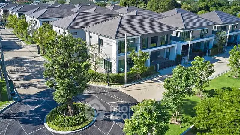 Luxurious modern residential complex with lush greenery and spacious roads.