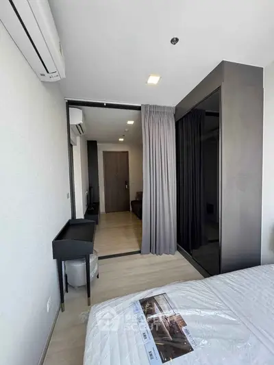 Modern bedroom with sleek design and large window, featuring a stylish wardrobe and air conditioning.
