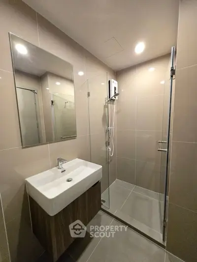 Modern bathroom with glass shower and sleek vanity in contemporary apartment.