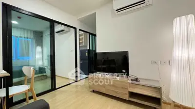 Modern living room with sleek furniture and glass partition leading to bedroom