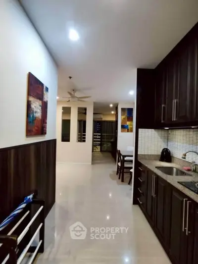 Modern kitchen with dark wood cabinets and open layout leading to dining area.