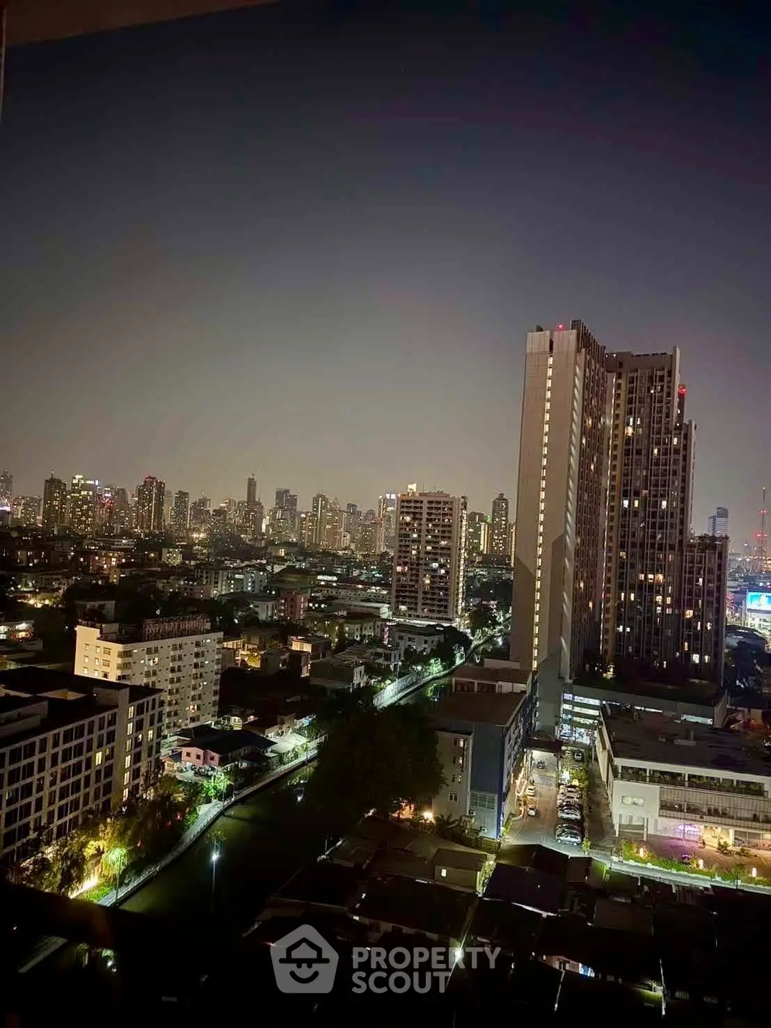 Stunning cityscape view from high-rise apartment balcony at night, showcasing vibrant urban skyline.