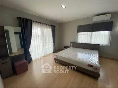 Spacious bedroom with large windows and modern furnishings, perfect for comfortable living.
