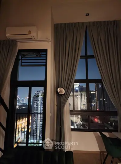 Stunning high-rise apartment with floor-to-ceiling windows offering breathtaking city views at night.