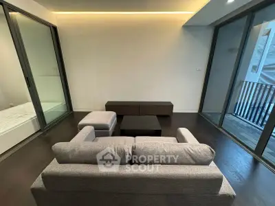 Modern living room with sleek furniture and large glass doors leading to a balcony.