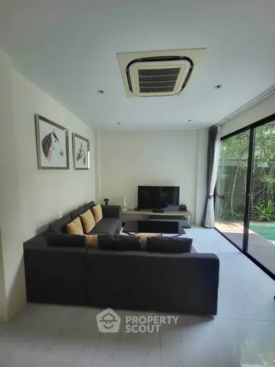 Modern living room with sleek furniture and large sliding glass doors opening to a lush garden view.