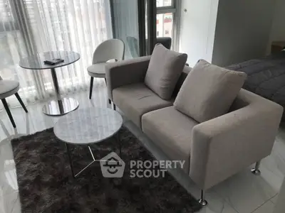 Modern living room with cozy sofa, stylish tables, and plush rug in a bright apartment.