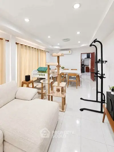 Spacious living room with modern furniture and cat tree, perfect for relaxation and entertainment.