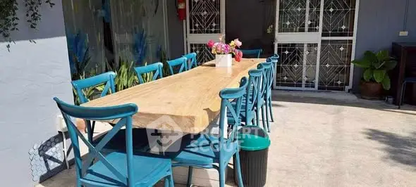 Charming outdoor dining area with rustic wooden table and vibrant blue chairs, perfect for entertaining.