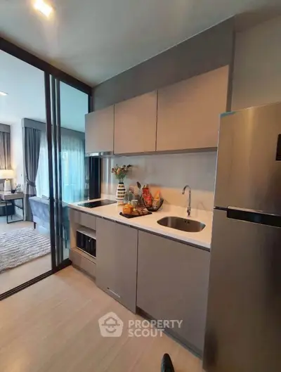 Modern kitchen with sleek cabinetry and stainless steel appliances in open layout apartment.