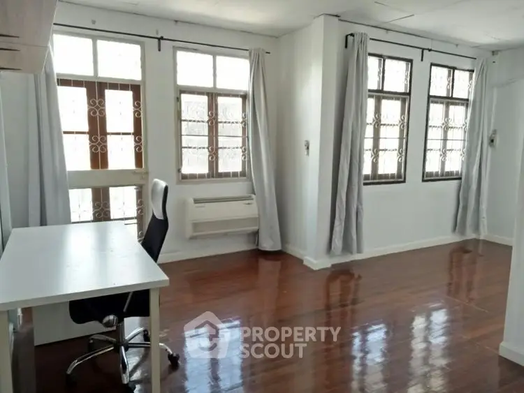 Spacious study room with wooden floors and large windows for natural light