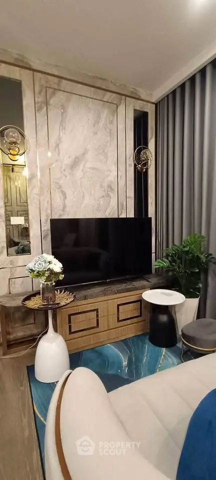 Luxurious living room with modern decor, featuring a large TV, elegant marble wall, and stylish furniture.