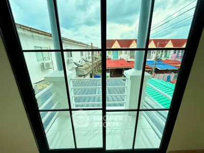 Charming balcony view with colorful rooftops and cloudy sky, perfect for relaxation.