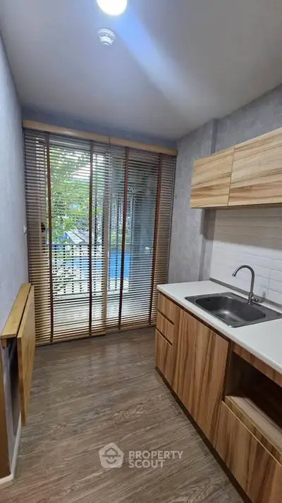 Modern kitchen with wooden cabinets and large window overlooking garden