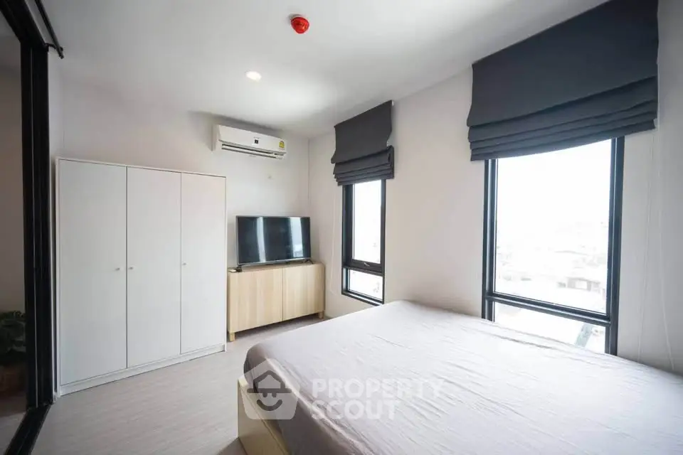 Bright and modern bedroom with large windows and sleek furnishings in a contemporary apartment.