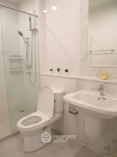 Modern bathroom with glass shower and sleek fixtures in contemporary apartment.