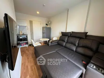 Modern living room with sleek black sofa and wall-mounted TV in cozy apartment.