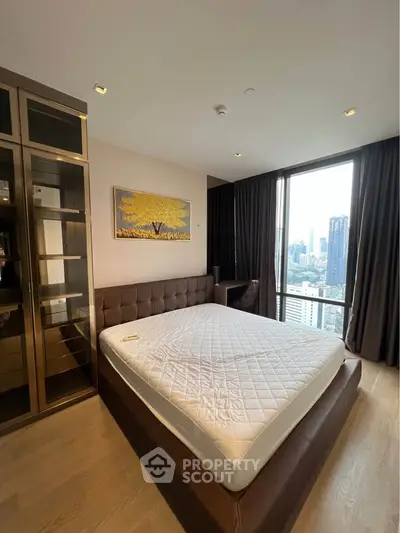 Luxurious bedroom with city view, featuring a large bed and modern glass wardrobe.