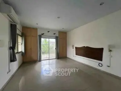 Spacious unfurnished bedroom with large windows and balcony access in modern apartment.