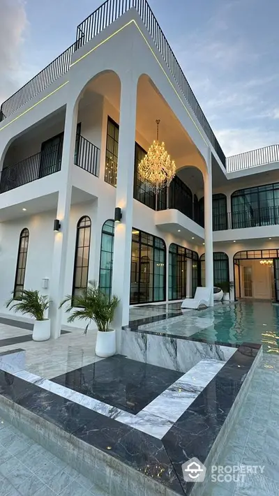 Luxurious modern villa with elegant pool and stunning architecture, featuring high ceilings and a grand chandelier.