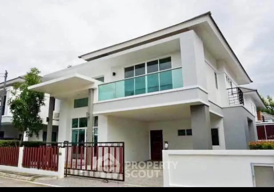 Modern two-story house with sleek design and large windows, featuring a spacious balcony and contemporary architecture.